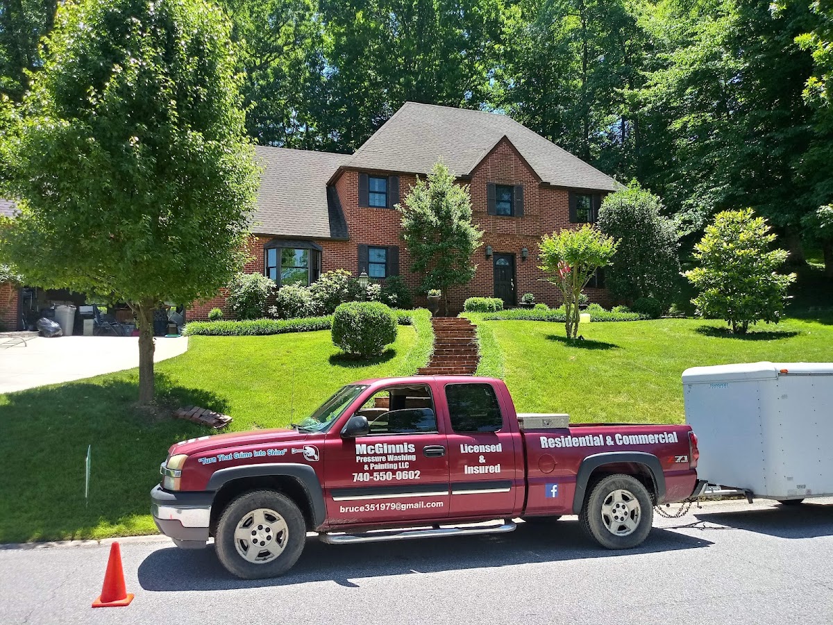 McGinnis Pressure Washing pickup truck and trailer outside a brick home