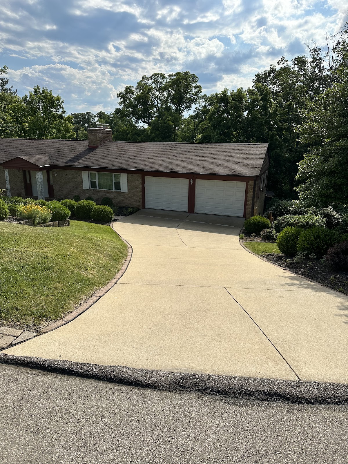 Freshly cleaned concrete driveway at a brick ranch home